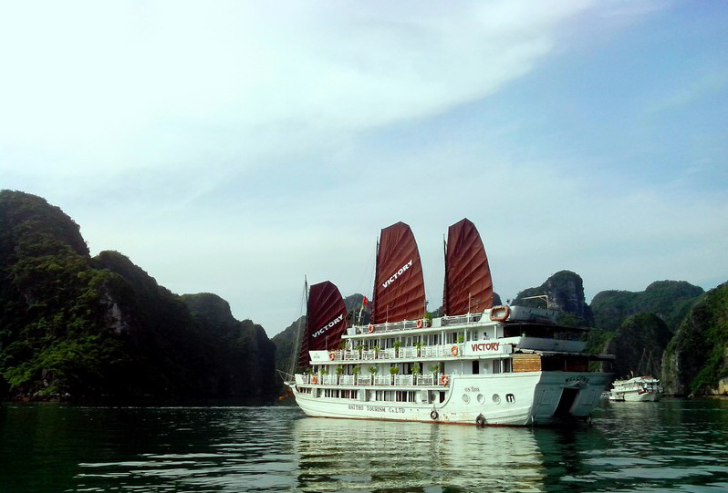 A cruise boat is dwarfed by one of the limestone karsts